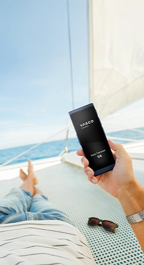 A person relaxing on a yacht, holding a Vasco Translator V4 in hand, with the sea visible in the background.