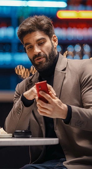 A man with a Vasco Translator E1 in his ear and a Vasco V4 in his hand, demonstrating one-button translation.