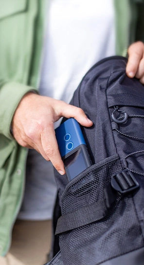 A person putting the Vasco Translator M3 into their pocket — a compact device known for its long-lasting battery.