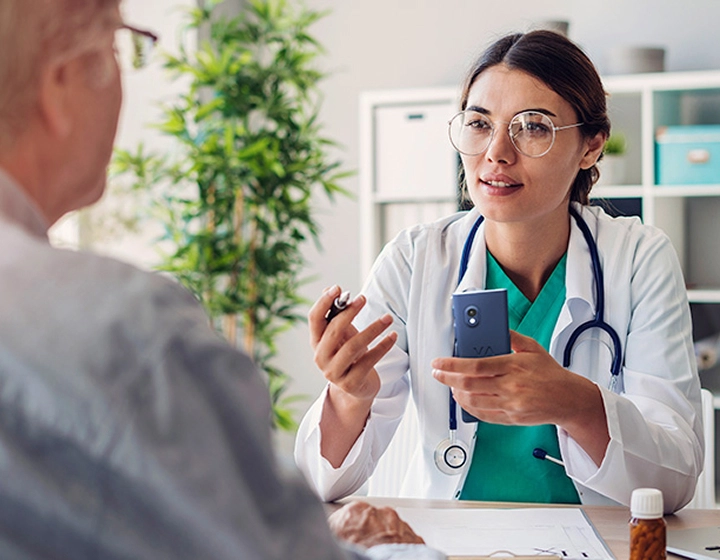 Female doctor holding the Vasco V4 translator and speaking to a patient during consultation.