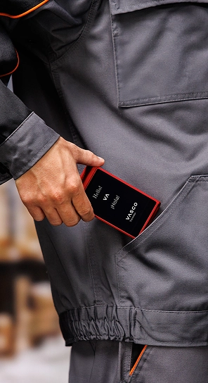 A person putting the Vasco Translator Q1 into their pocket — a compact device known for its long-lasting battery.
