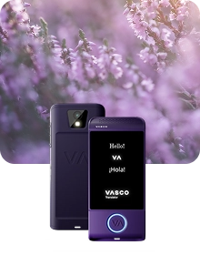 A product showcase image featuring a black Vasco Translator device from two angles against a dark, textured fabric background. The device on the left shows the back view, highlighting a camera lens with a flash and an embossed 