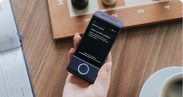 A top-down shot of a person's hand holding a purple Vasco electronic translator over a wooden table. The device's screen displays a 